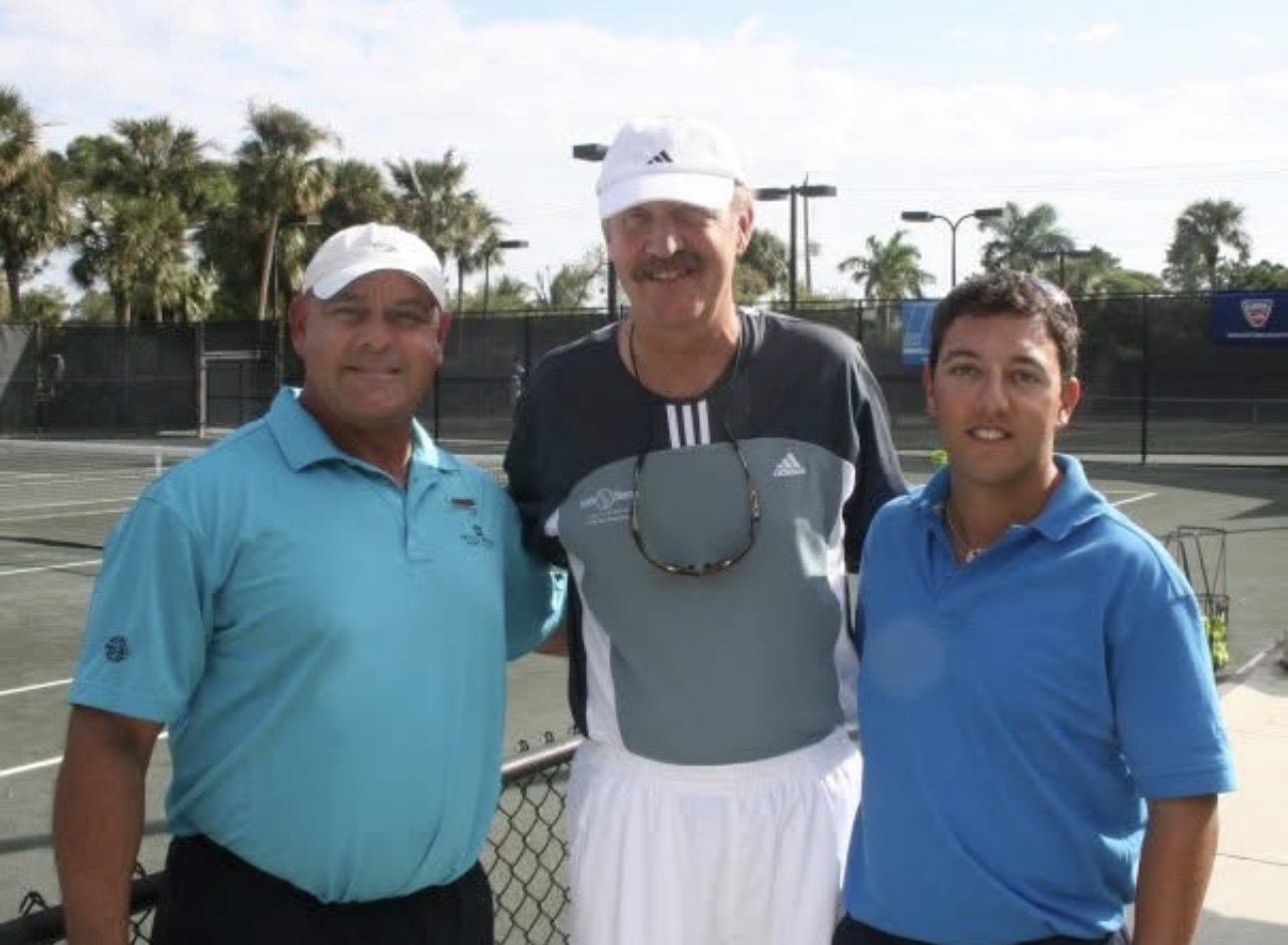 Mike Manzella with two veteran coaches on a hard court lined with palm trees
