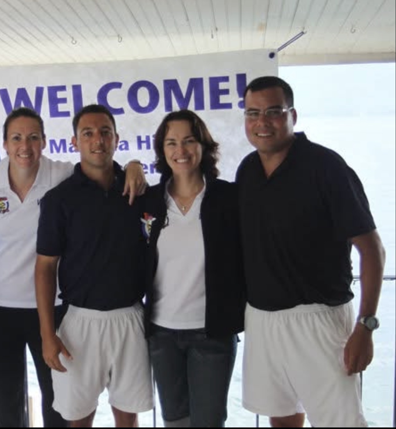 Mike Manzella with club teaching staff in front of a welcome banner